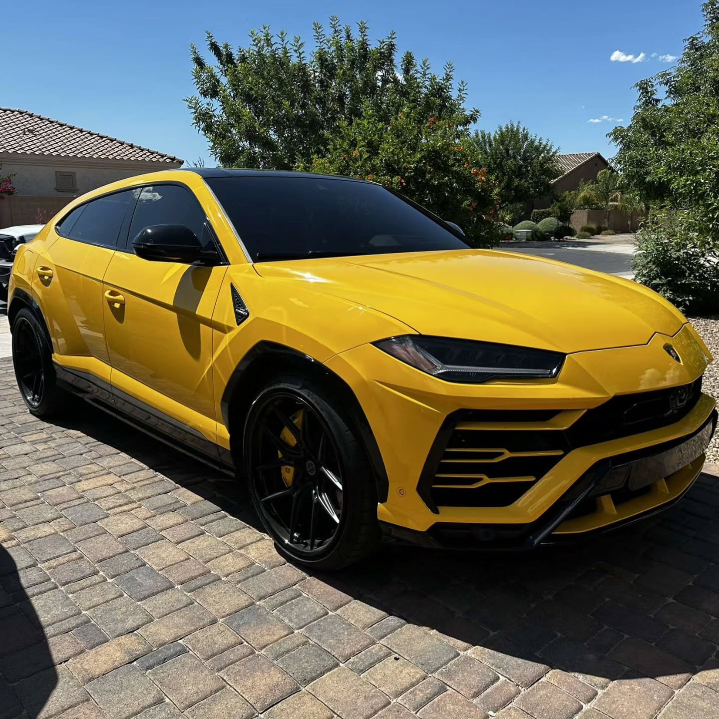 Yellow Lamborghini Urus with dark window tint outside a home